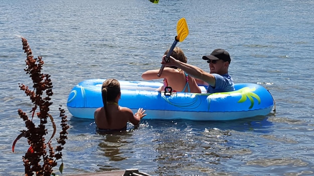 Padre e hija en un bote inflable por una niña en el río durante un día soleado