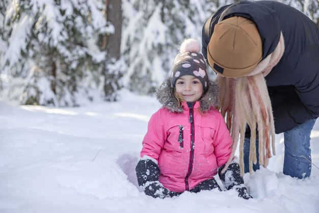 Padre e hija caminando y divirtiéndose en el bosque nevado en invierno