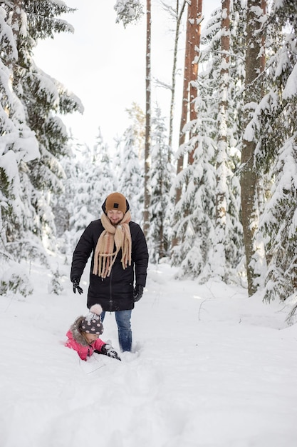 Padre e hija caminando y divirtiéndose en el bosque nevado en invierno