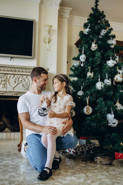 Padre e hija cerca del árbol de Navidad