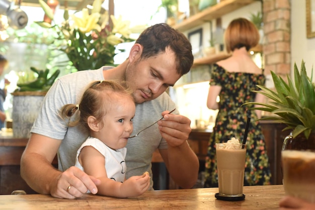 Padre e hija comiendo crema de frappe en un café