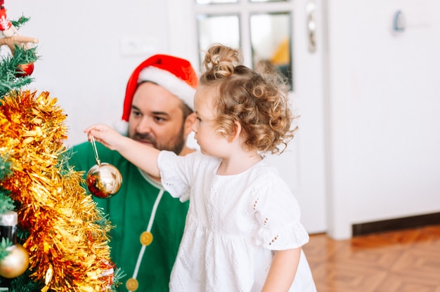 Padre e hija decorando el árbol de Navidad