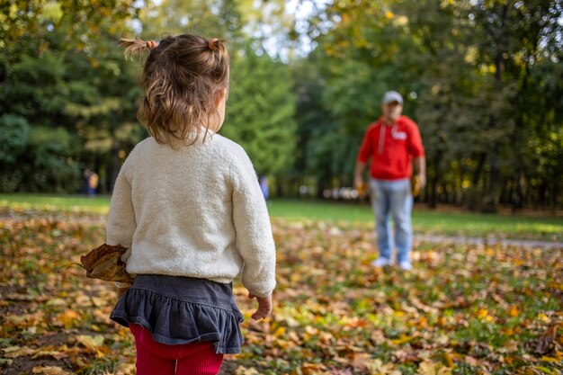 Padre e hija divirtiéndose en el parque. Papá con niña pequeña en el parque de otoño