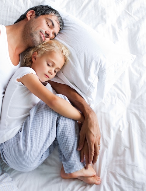 Padre e hija durmiendo en la cama