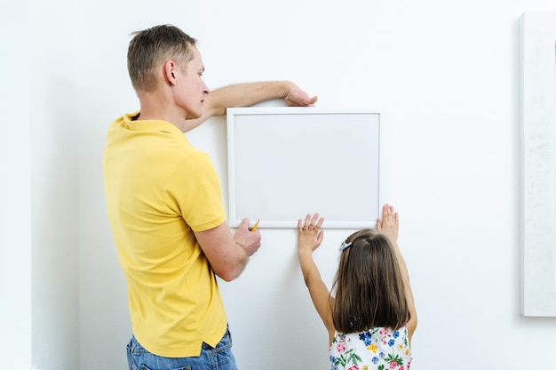 Padre e hija están decidiendo dónde colgará la imagen.