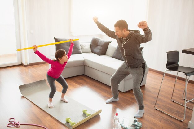 Padre e hija están entrenando en casa. Entrenamiento en el departamento.