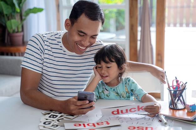 Padre e hija estudian juntos usando un teléfono inteligente