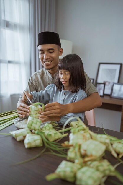 Padre e hija haciendo ketupat juntos en casa