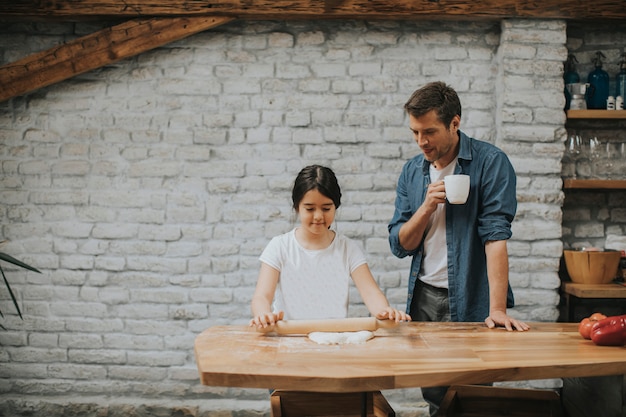 Padre e hija haciendo pan en la cocina rústica