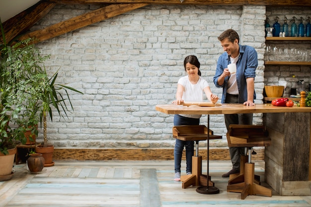 Padre e hija haciendo pan en la cocina rústica