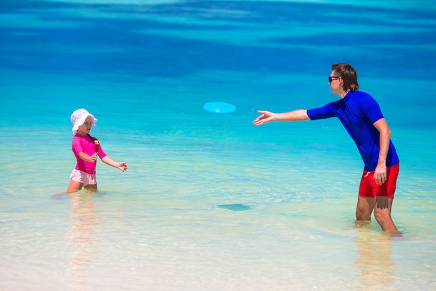 Padre e hija jugando con disco volador en la playa