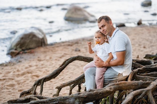 Foto padre e hija juntos en la playa en la naturaleza una niña come raíces de un árbol de piruletas