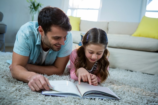 Padre e hija leyendo un libro en la sala de estar