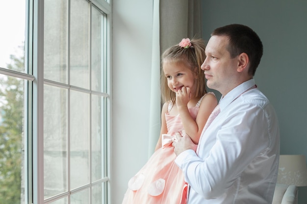 Padre e hija mirando la ventana juntos en casa