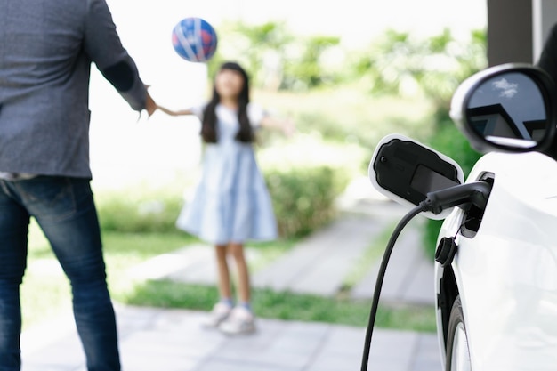 Foto padre e hija progresivos cargando autos ev desde la estación de carga doméstica