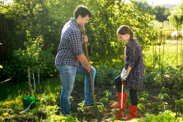 Padre e hija spudding cama de jardín con palas en día soleado