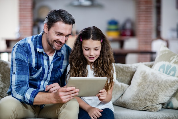 Padre e hija con tableta digital en la sala de estar