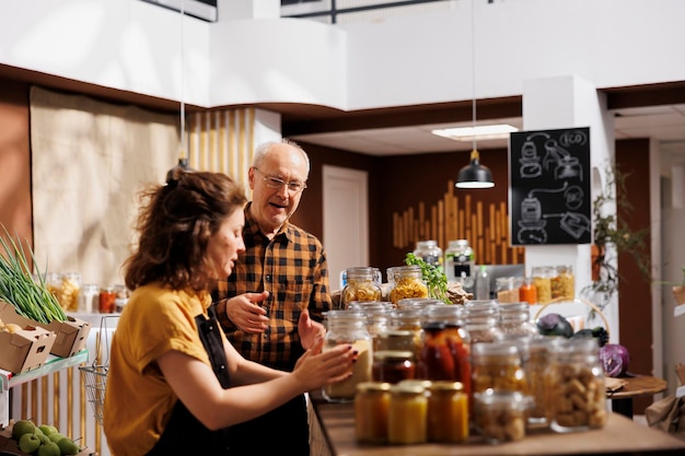 Padre e hija en tienda ambientalmente responsable con desperdicio cero interesados en comprar alimentos con alto valor nutricional. Clientes que buscan productos básicos de despensa en envases reutilizables y ecológicos