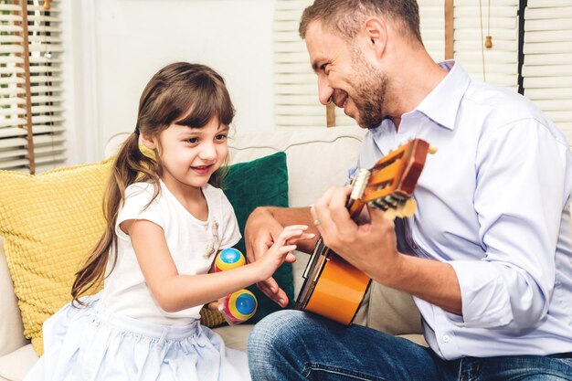 Foto padre e hija tocando la guitarra en el sofá en casa