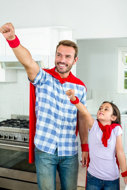 Padre e hija en traje de superhéroe con mano levantada