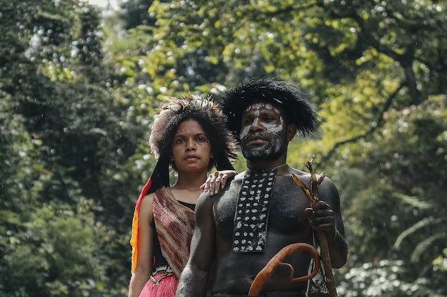 Padre e hija de la tribu Dani con ropa tradicional de pie juntos en el bosque verde Papúa