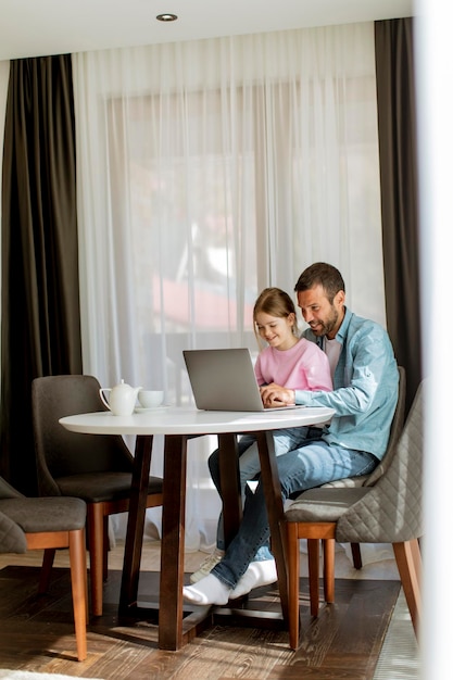 Padre e hija usando una computadora portátil juntos en la habitación