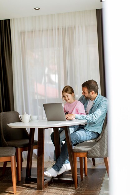 Padre e hija usando una computadora portátil juntos en la habitación