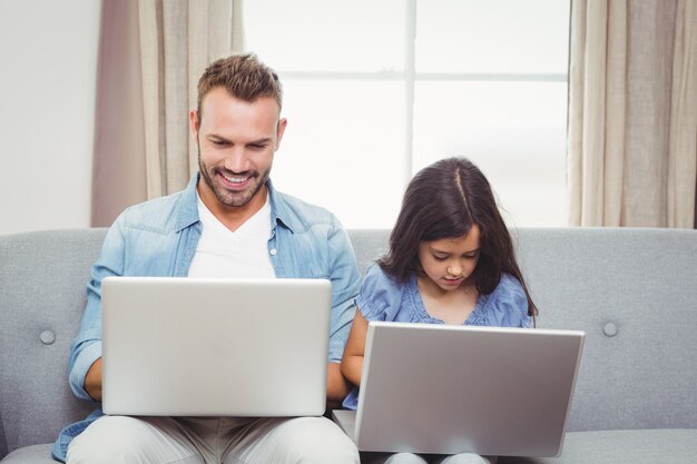 Padre e hija usando laptop en casa