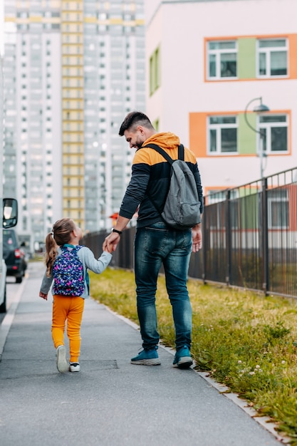 Padre e hija van a la escuela por primera vez. Regreso a la escuela después de la pandemia.