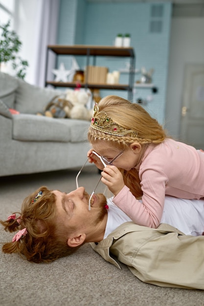 Padre e hija vistiendo lindos disfraces divirtiéndose y jugando juntos en el piso