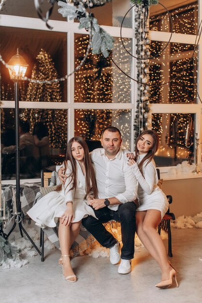 padre e hijas cerca del árbol de navidad