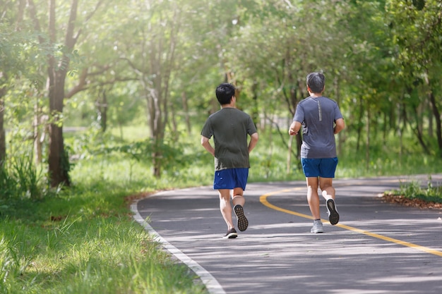 Padre e hijo adulto trotar en el sendero del parque