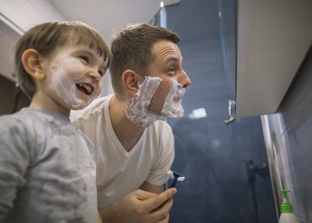 Foto padre e hijo afeitándose la barba en el baño.