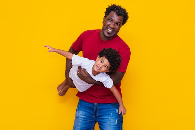 Padre e hijo afro sobre fondo amarillo sonriendo y jugando. Concepto del día del padre