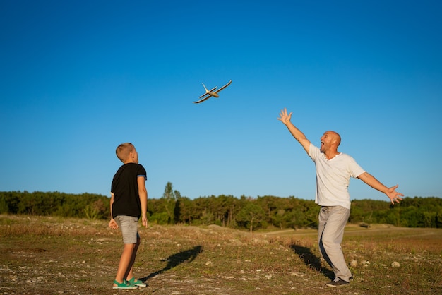 Padre e hijo alegres están jugando en avión en la naturaleza