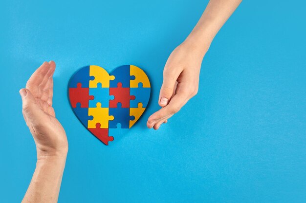 Padre e hijo autista manos sosteniendo rompecabezas en forma de corazón día mundial de concientización sobre el autismo