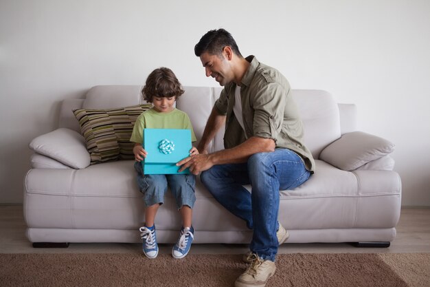 Padre e hijo con caja de regalo sentado en la sala de estar