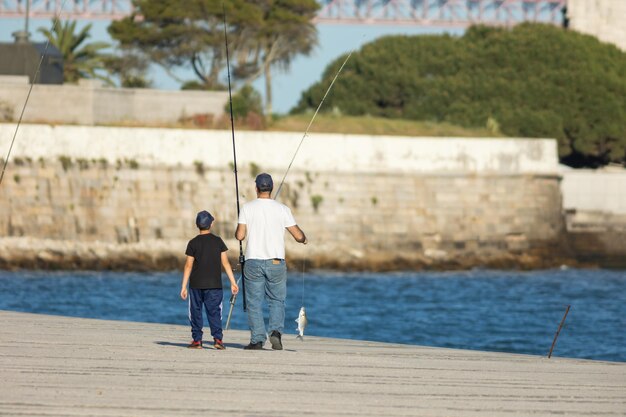 Padre e hijo caminando por el muelle con peces colgando de un sedal