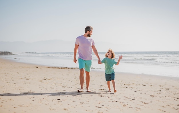 Padre e hijo caminando en la playa de verano papá con niño en un día de verano papá e hijo disfrutando