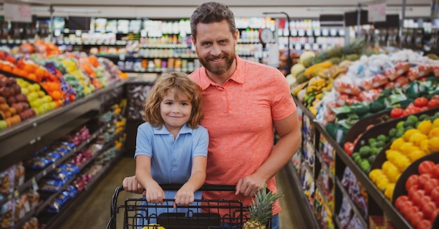 Padre e hijo con carrito de compras en el supermercado eligiendo comida