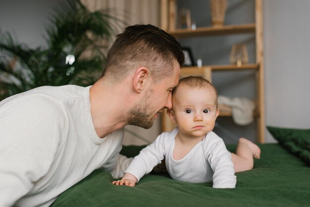 Padre e hijo caucásicos en el dormitorio en la cama Papá se acurruca con su bebé