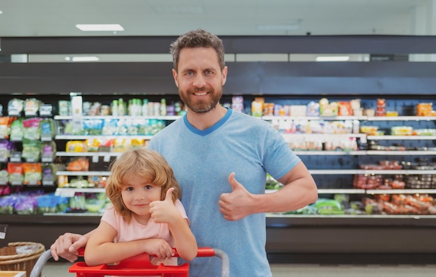 Padre e hijo compran verduras frescas en la tienda de comestibles con pulgares arriba familia en la tienda