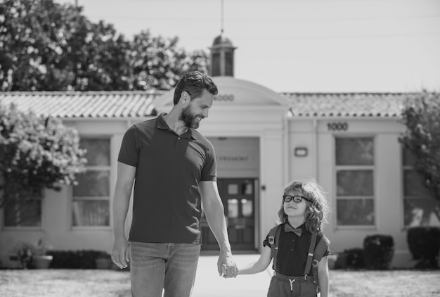 Padre e hijo corren con el padre después de regresar de la escuela, la educación de los niños de la escuela y el concepto al aire libre