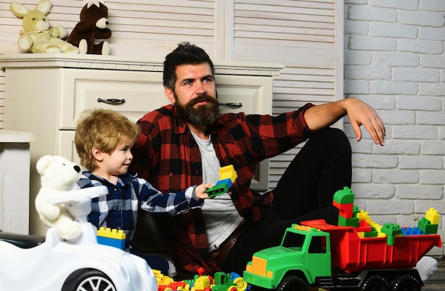 Padre e hijo crean juguetes de ladrillos lindo niño pequeño hijo juega coches de juguete con papá familia feliz hijo