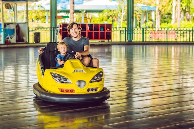 Padre e hijo dando un paseo en el coche de choque en el parque de atracciones