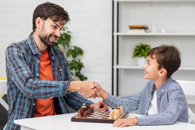 Foto padre e hijo dándose la mano antes del ajedrez