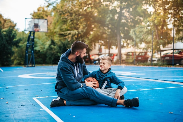 Padre e hijo disfrutando juntos en la cancha de baloncesto.