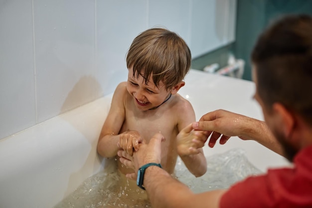 Padre e hijo se divierten en el baño mientras bañan a su hijo