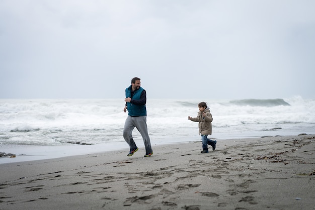 Padre e hijo se divierten en la playa de invierno