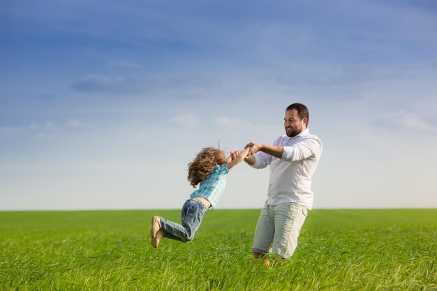 Padre e hijo divirtiéndose al aire libre en el campo de primavera contra el cielo azul